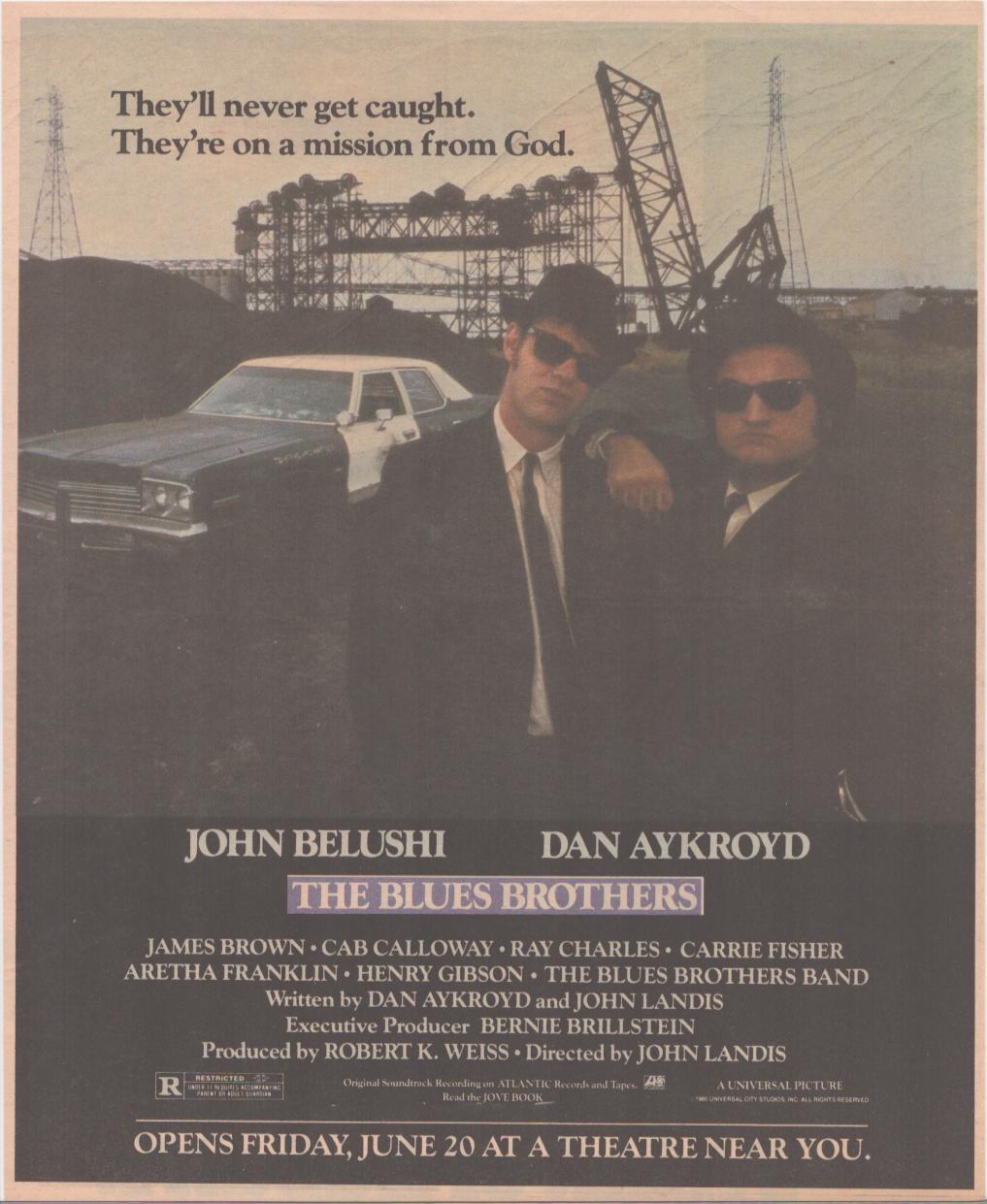 Vintage 1980 Blues Brothers original print advertisement, John Belushi and Dan Aykroyd in black suits and sunglasses leaning on the Bluesmobile with industrial skyline behind them