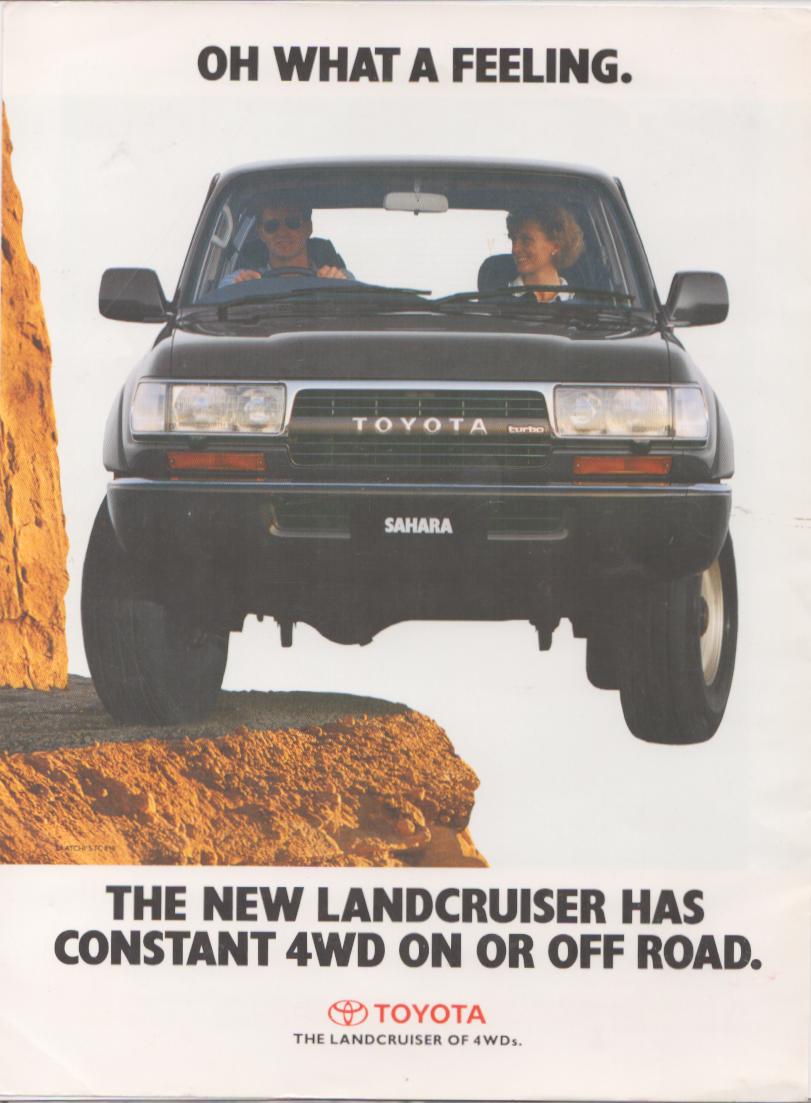 Vintage 1980s Toyota Land Cruiser Sahara Turbo original print advertisement, black SUV airborne over rocky terrain with two occupants, Oh What a Feeling slogan