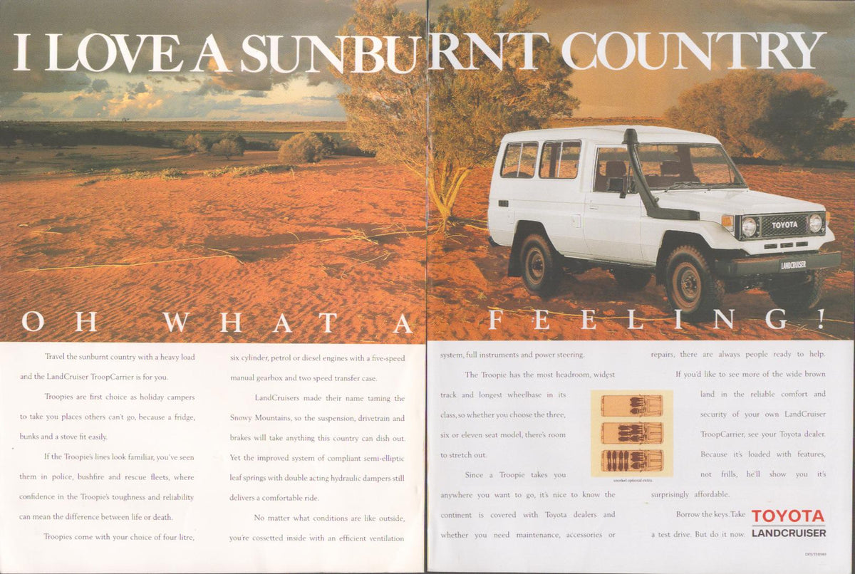 Vintage 1980s Toyota Land Cruiser Troopcarrier original print advertisement, white Troopcarrier on red Australian outback terrain under dramatic cloudy sky with 'I Love a Sunburnt Country' headline