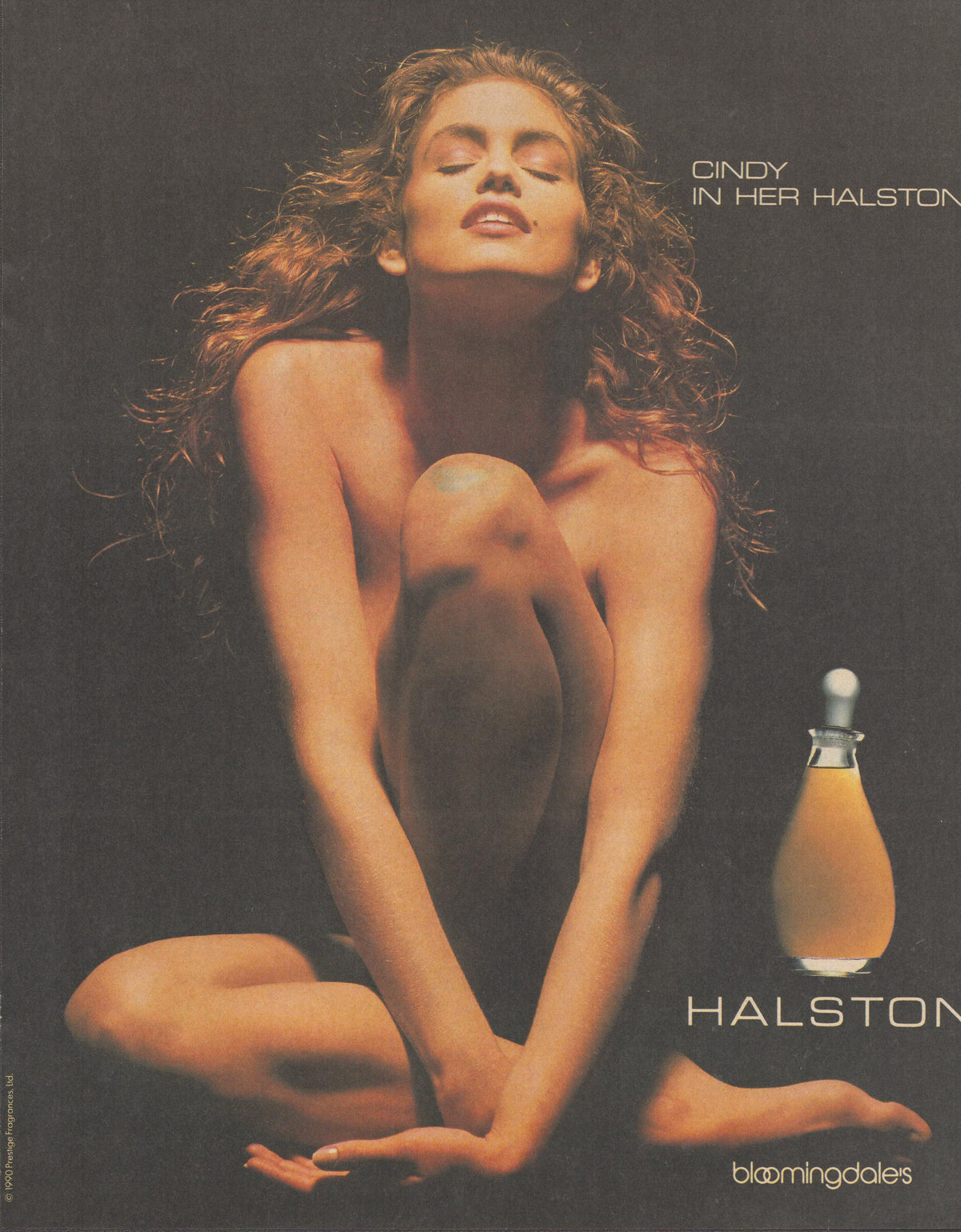 Vintage 1990 Halston fragrance original print advertisement, Cindy Crawford seated against dark background with Halston perfume bottle and Bloomingdale's branding