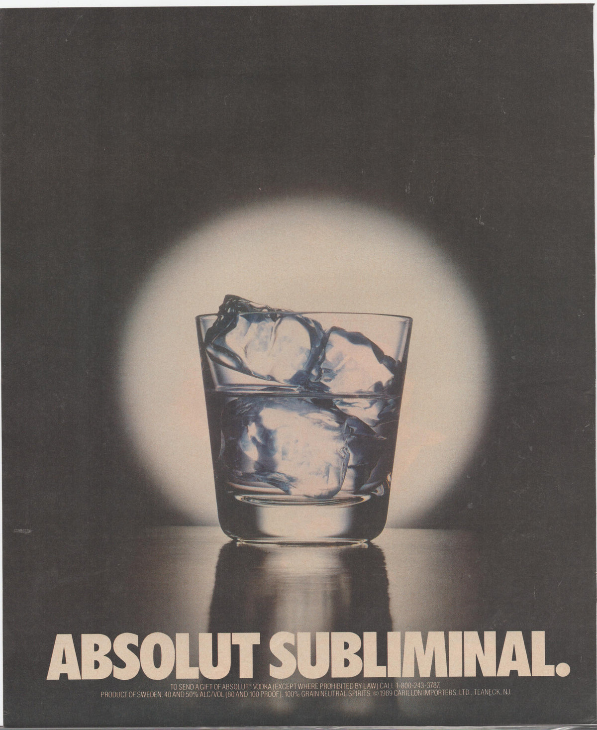 Vintage 1989 Absolut Vodka original print advertisement, spotlit rocks glass with ice on dark background with circular glow forming bottle silhouette, 'Absolut Subliminal' headline