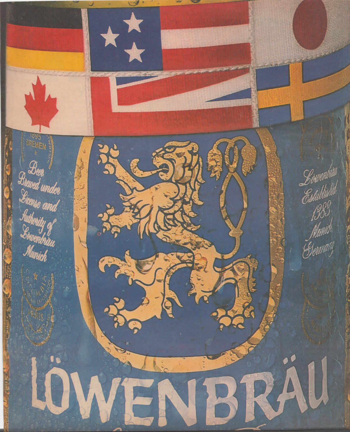 Vintage 1970s Löwenbräu original print advertisement, gold lion heraldic crest on blue shield surrounded by international flags including USA, Canada, Germany, UK, Japan, and Sweden