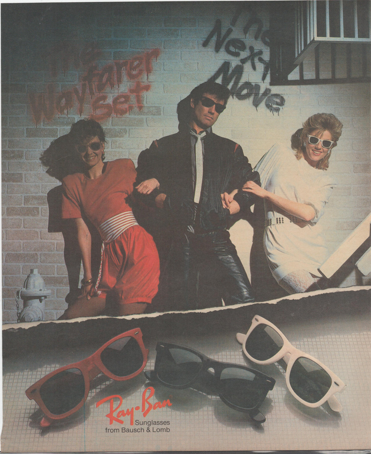 Vintage 1984 Ray-Ban Wayfarer original print advertisement, three models in 1980s street fashion against graffiti brick wall with red, black, and white Wayfarer sunglasses displayed below