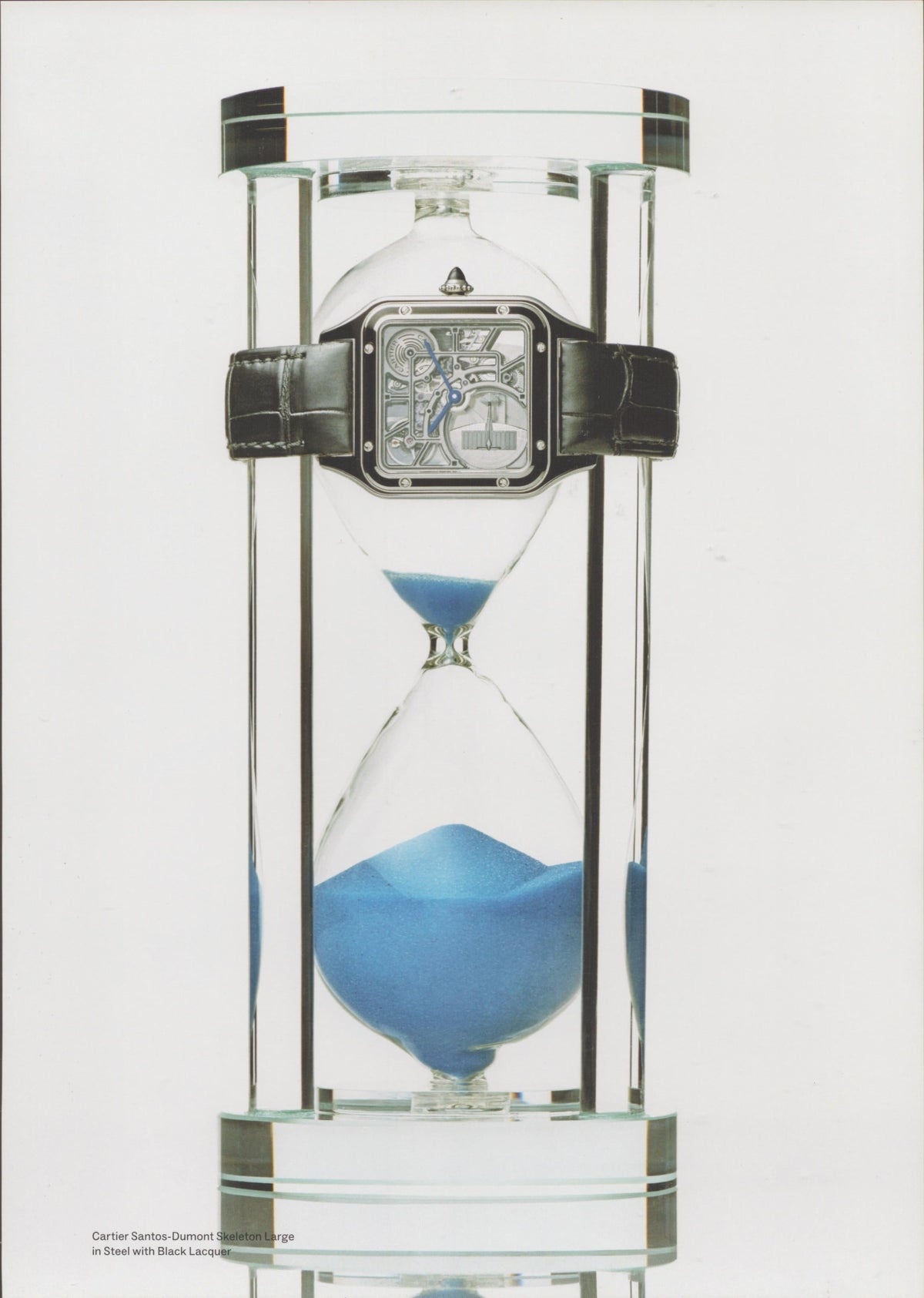 Vintage 2000s Cartier Santos-Dumont Skeleton Large original print advertisement, skeletonized watch suspended on glass hourglass with blue sand on white background
