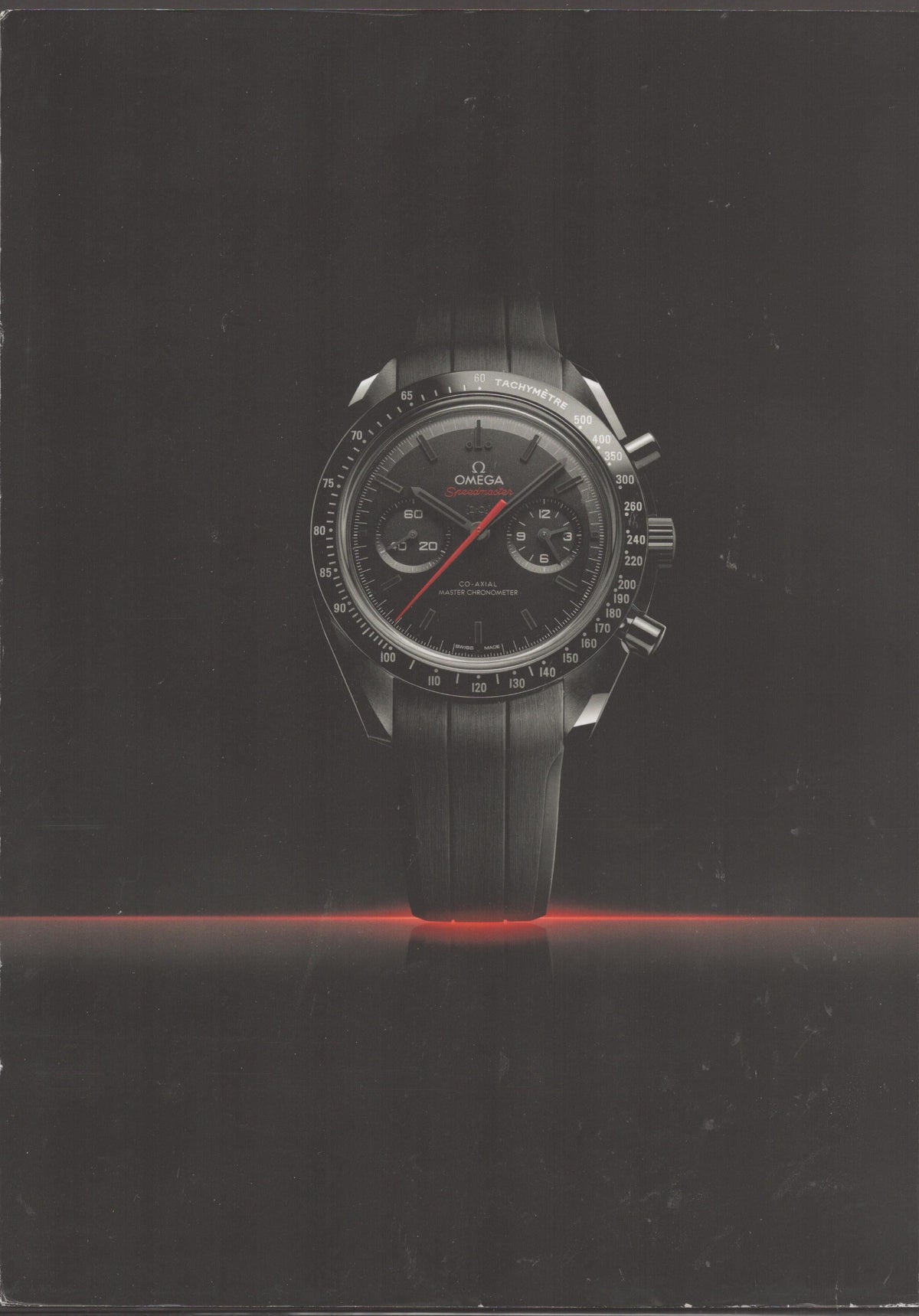 Vintage 2014 Omega Speedmaster Dark Side of the Moon original print advertisement, all-black ceramic chronograph floating on dark background with red horizon glow