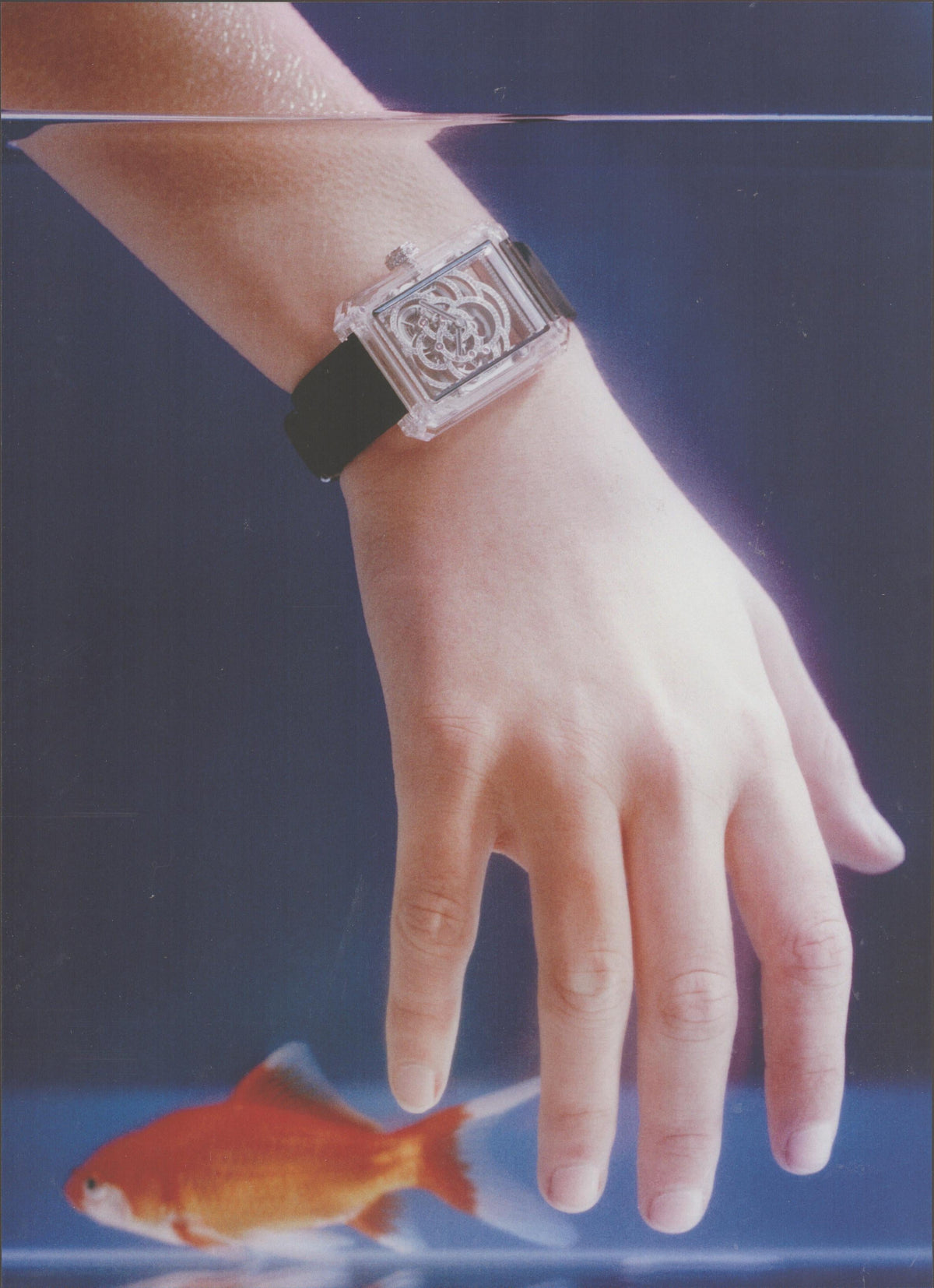 Vintage 1985 Guess clear skeleton-case watch original print advertisement, hand submerged in fish tank with goldfish, blue background