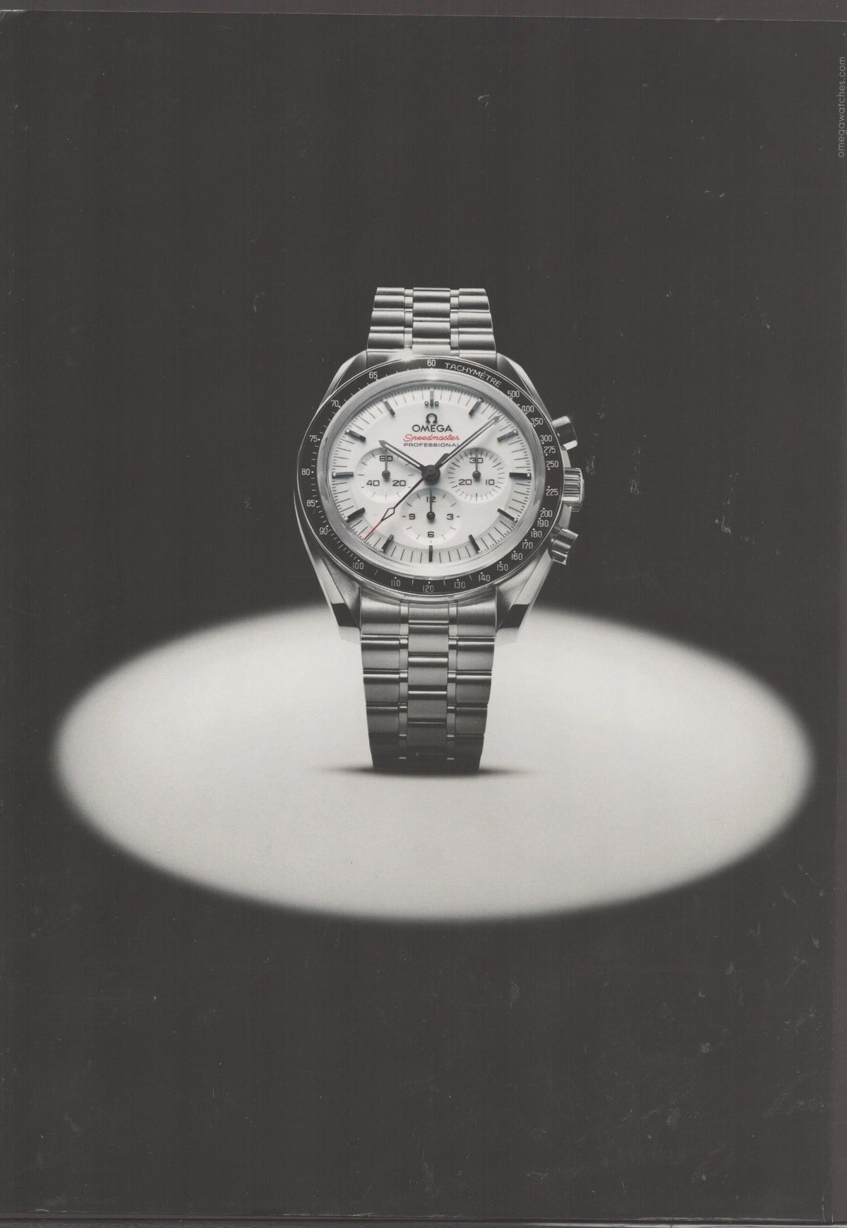 Vintage 1990s Omega Speedmaster Professional original print advertisement, stainless steel chronograph with white dial dramatically spotlit against black background