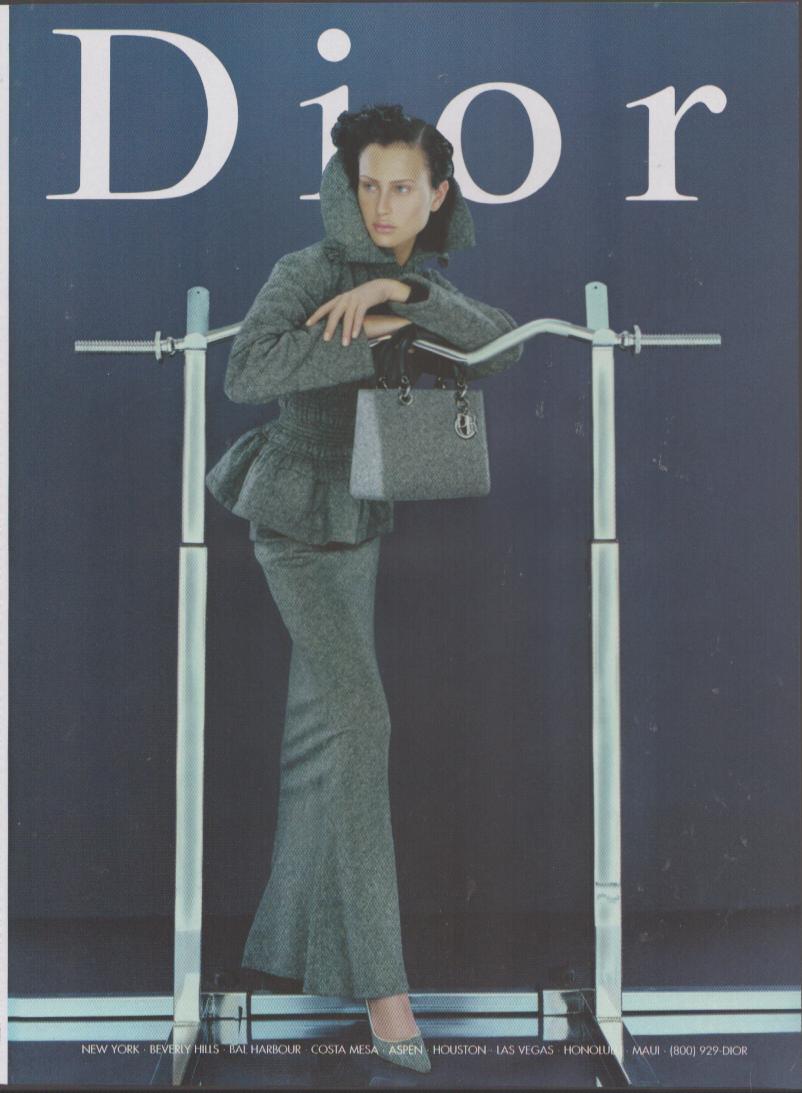 Vintage 1990s Christian Dior Lady Dior original print advertisement, model in grey wool suit holding Lady Dior bag against navy background