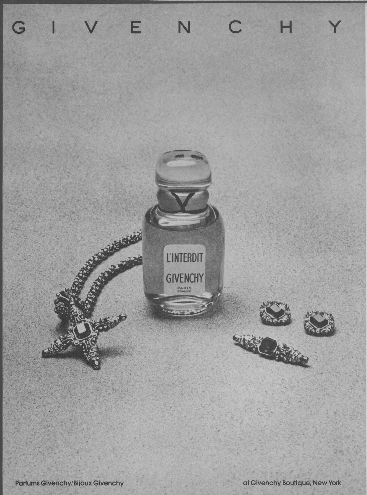 Vintage 1970s Givenchy L'Interdit original print advertisement, black and white still life of perfume bottle with Bijoux Givenchy starfish brooch and jeweled earrings