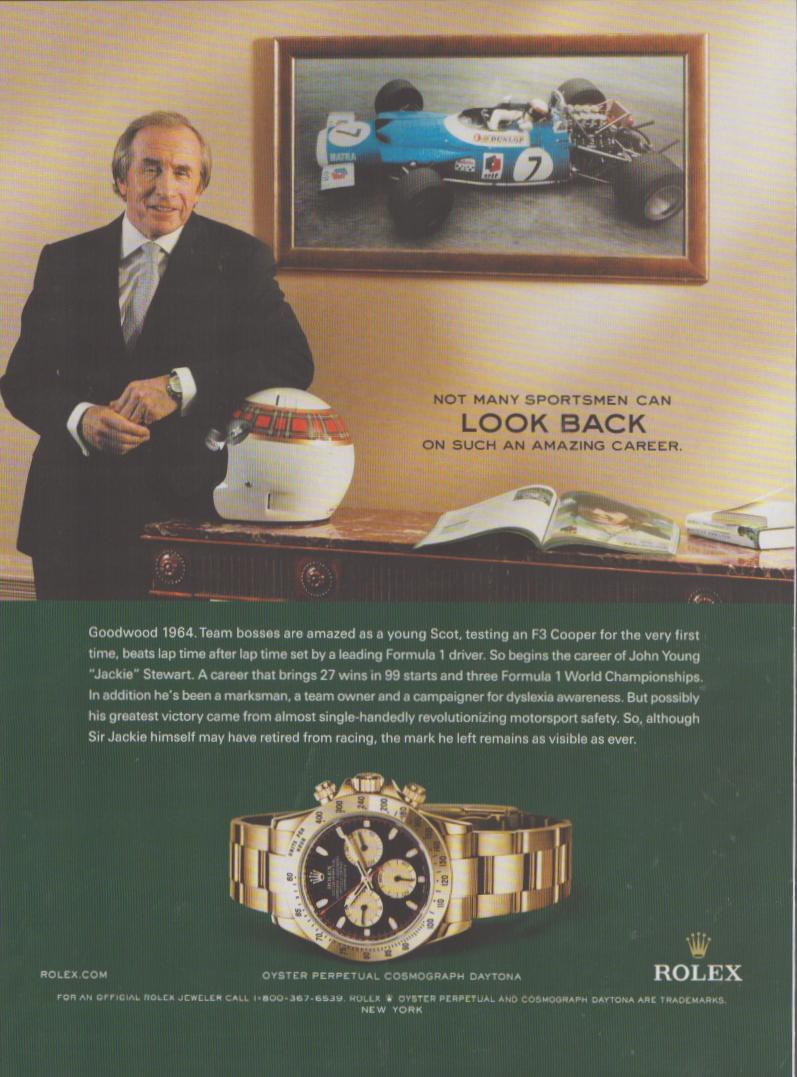 Vintage 2000s Rolex Daytona Cosmograph original print advertisement, Sir Jackie Stewart standing beside his F1 racing helmet with framed Matra photograph, yellow gold Daytona watch featured below on green background