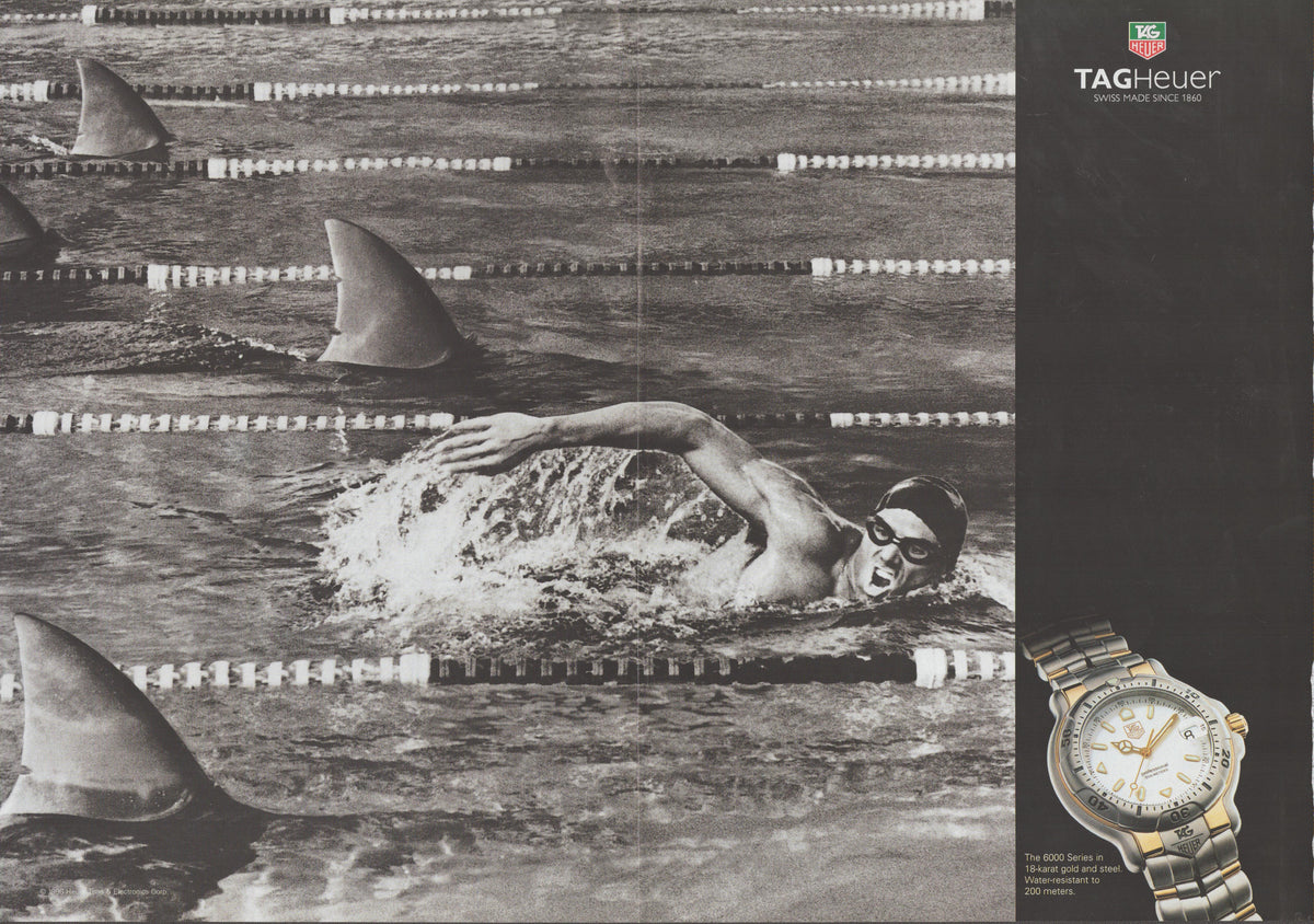 Vintage 1990s TAG Heuer Aquaracer original print advertisement, black and white swimmer racing through pool surrounded by shark fins with color watch image
