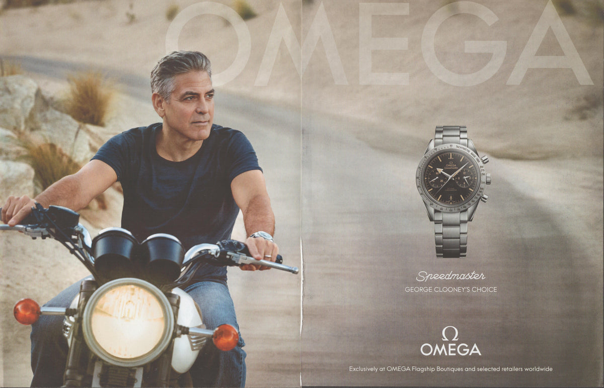 Vintage 2000s Omega Speedmaster original print advertisement, George Clooney on a vintage motorcycle in desert setting with Speedmaster chronograph inset