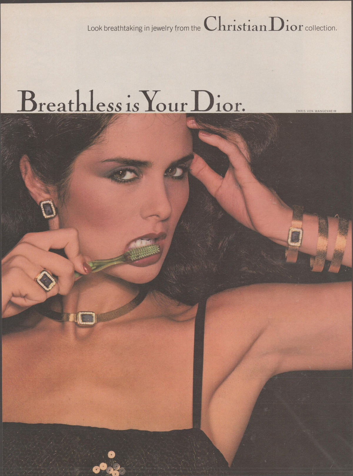 Vintage 1970s Christian Dior jewelry collection original print advertisement, dark-haired model wearing gold and gemstone choker, cuff, ring, and earrings in provocative editorial pose
