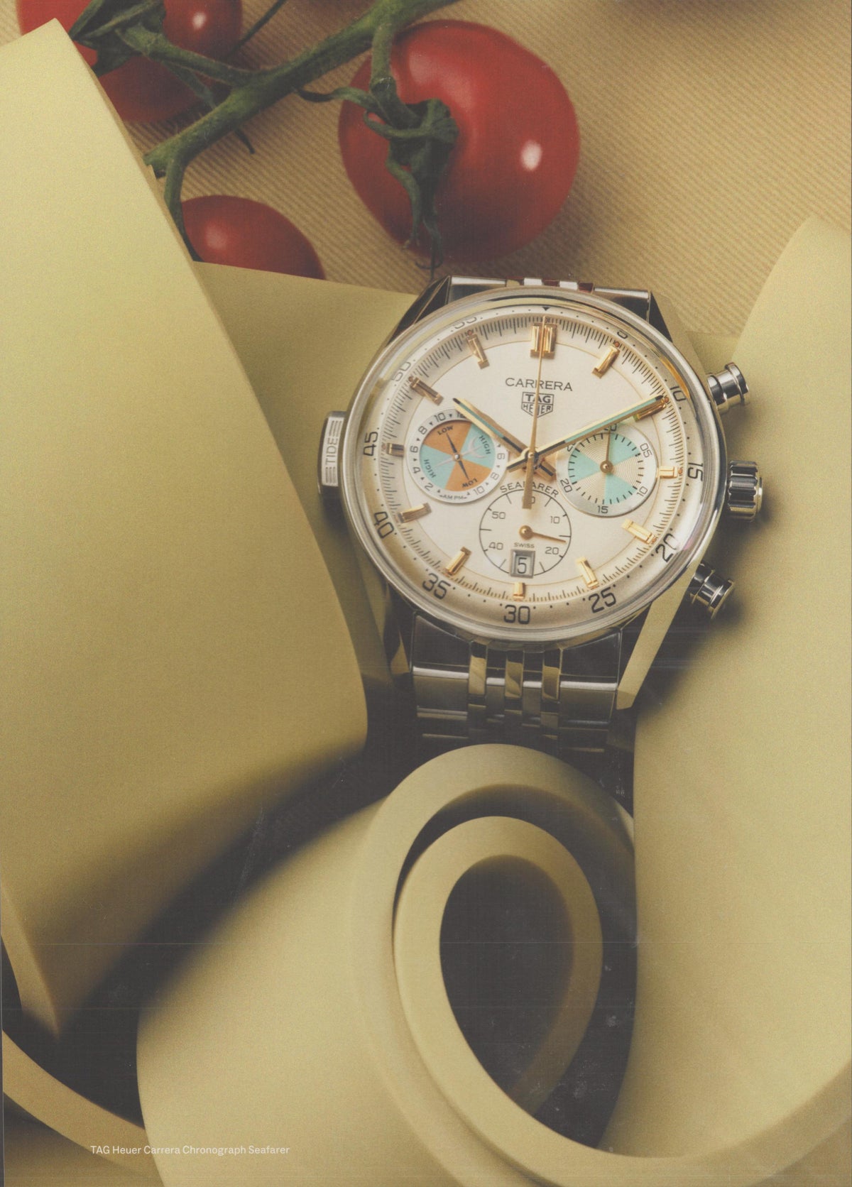 Vintage 1990s TAG Heuer Carrera Chronograph Seafarer original print advertisement, cream dial chronograph on steel bracelet surrounded by cream ribbon and cherry tomatoes