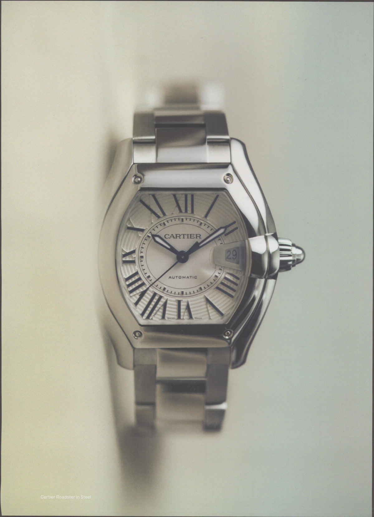 Vintage 2002 Cartier Roadster Automatic original print advertisement, stainless steel watch on neutral soft-focus background with silver guilloché dial and Roman numerals