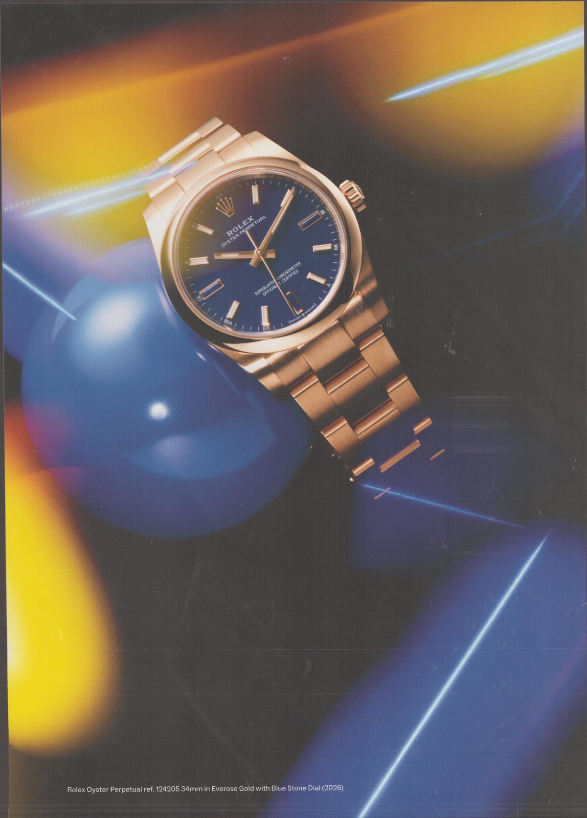 Vintage 2026 Rolex Oyster Perpetual Ref. 124205 original print advertisement, Everose gold 34mm watch with blue stone dial against abstract colorful light background