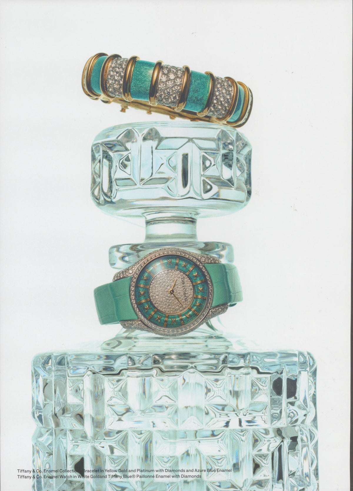 Vintage 1990s Tiffany & Co. Enamel Collection original print advertisement, diamond and azure enamel bracelet and paillonné enamel watch draped over a cut-crystal decanter on white background