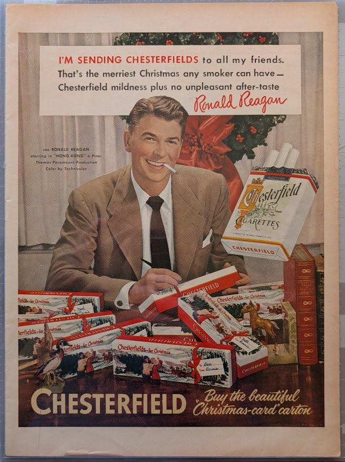 Vintage 1950s Chesterfield cigarettes original print advertisement featuring Ronald Reagan in suit endorsing cigarettes for Christmas with holiday cartons displayed