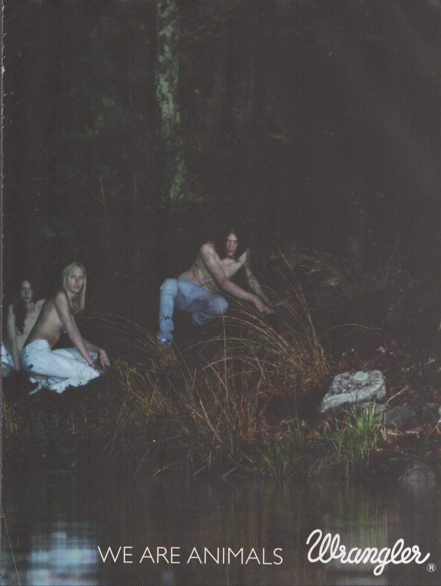 Vintage 2000s Wrangler 'We Are Animals' original print advertisement, dark moody forest scene with models in denim crouching by a woodland stream