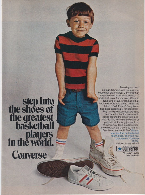 Vintage 1970s Converse All Star original print advertisement, young boy in red striped shirt standing between oversized Converse sneakers with bold basketball headline
