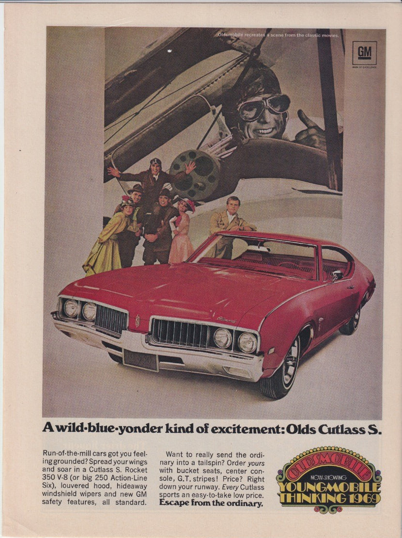 Vintage 1969 Oldsmobile Cutlass S original print advertisement, red coupe posed in front of classic aviation movie scene with costumed actors and biplane backdrop