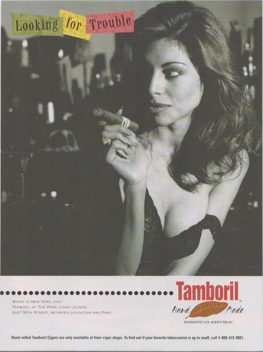 Vintage 1990s Tamboril Hand Made Dominican Republic original print advertisement, black and white photo of glamorous woman holding cigar in candlelit lounge with 'Looking for Trouble' headline