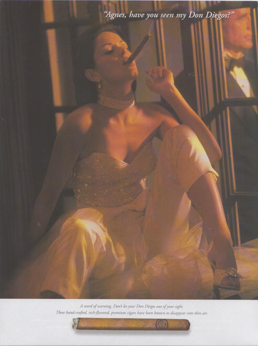 Vintage 1980s Don Diego cigar original print advertisement, elegantly dressed woman in strapless gown smoking a cigar while tuxedoed man searches in background