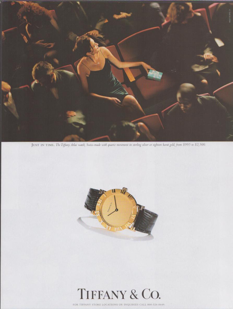 Vintage 1990s Tiffany & Co. Atlas Watch original print advertisement, overhead theater scene with woman holding blue Tiffany box above product shot of 18-karat gold Atlas watch on black lizard strap