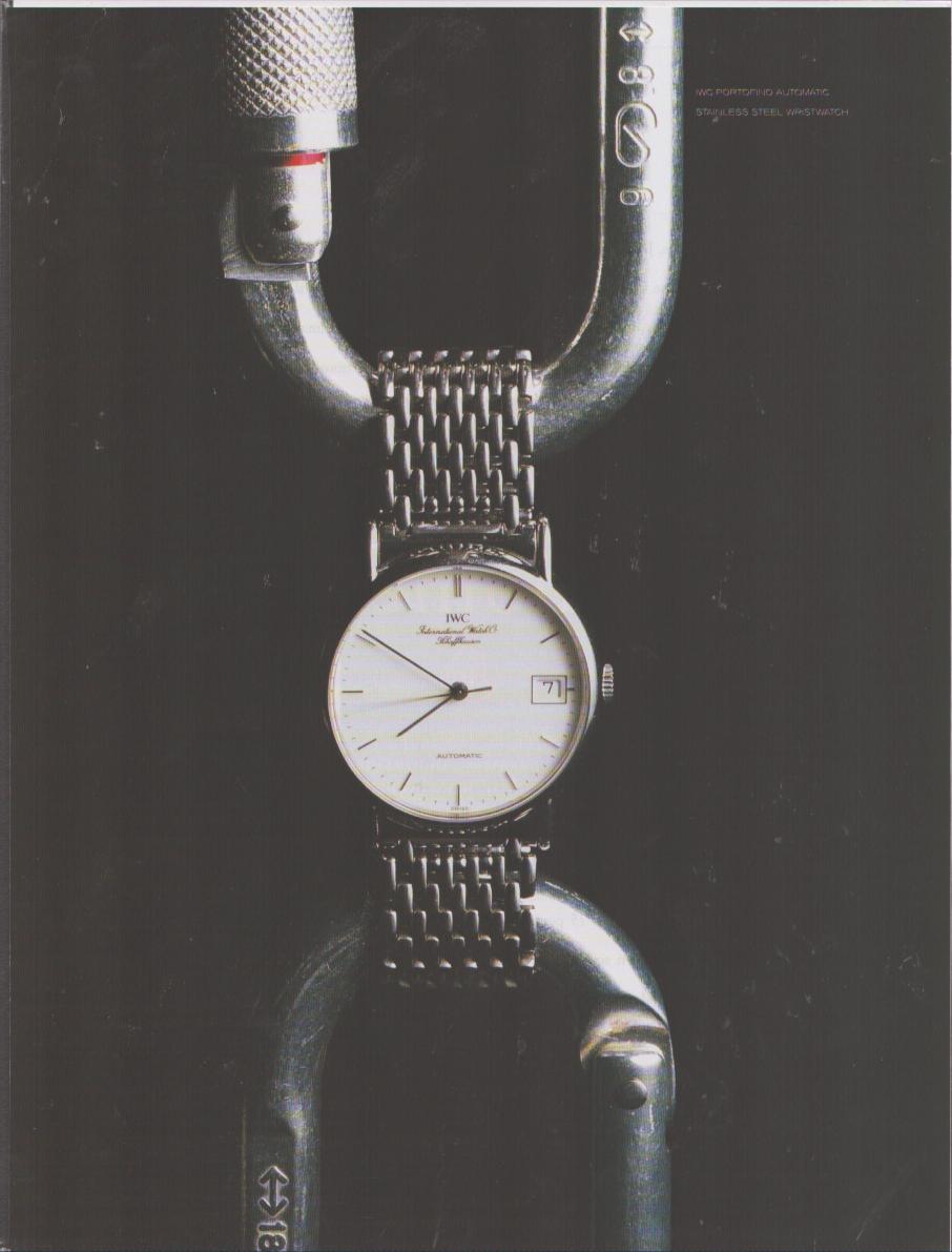 Vintage 1980s IWC Portofino Automatic original print advertisement, stainless steel watch with mesh bracelet suspended through an industrial shackle on dark background