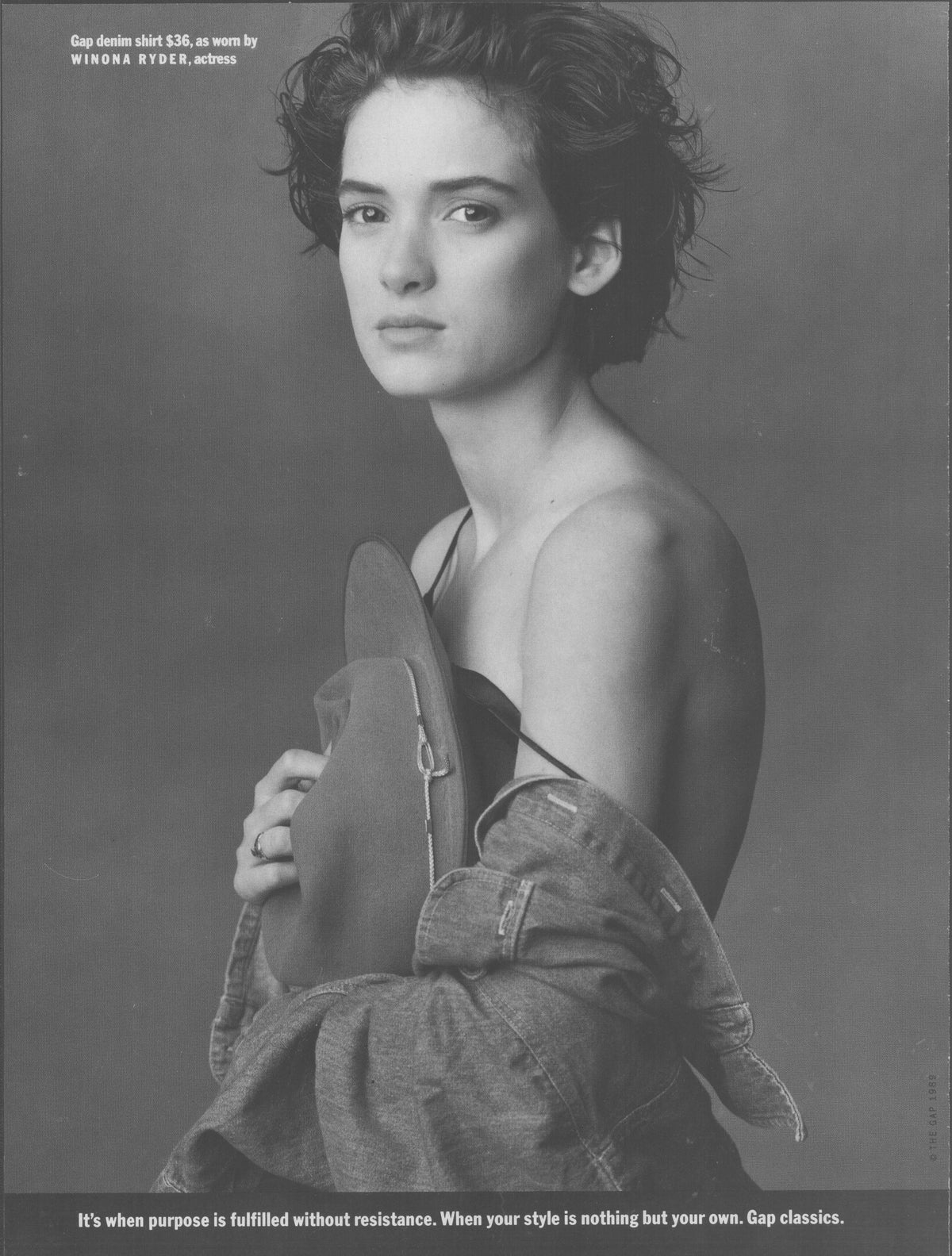 Vintage 1990s Gap denim original print advertisement, black and white portrait of Winona Ryder holding denim shirt off shoulder with tagline 'Gap classics'